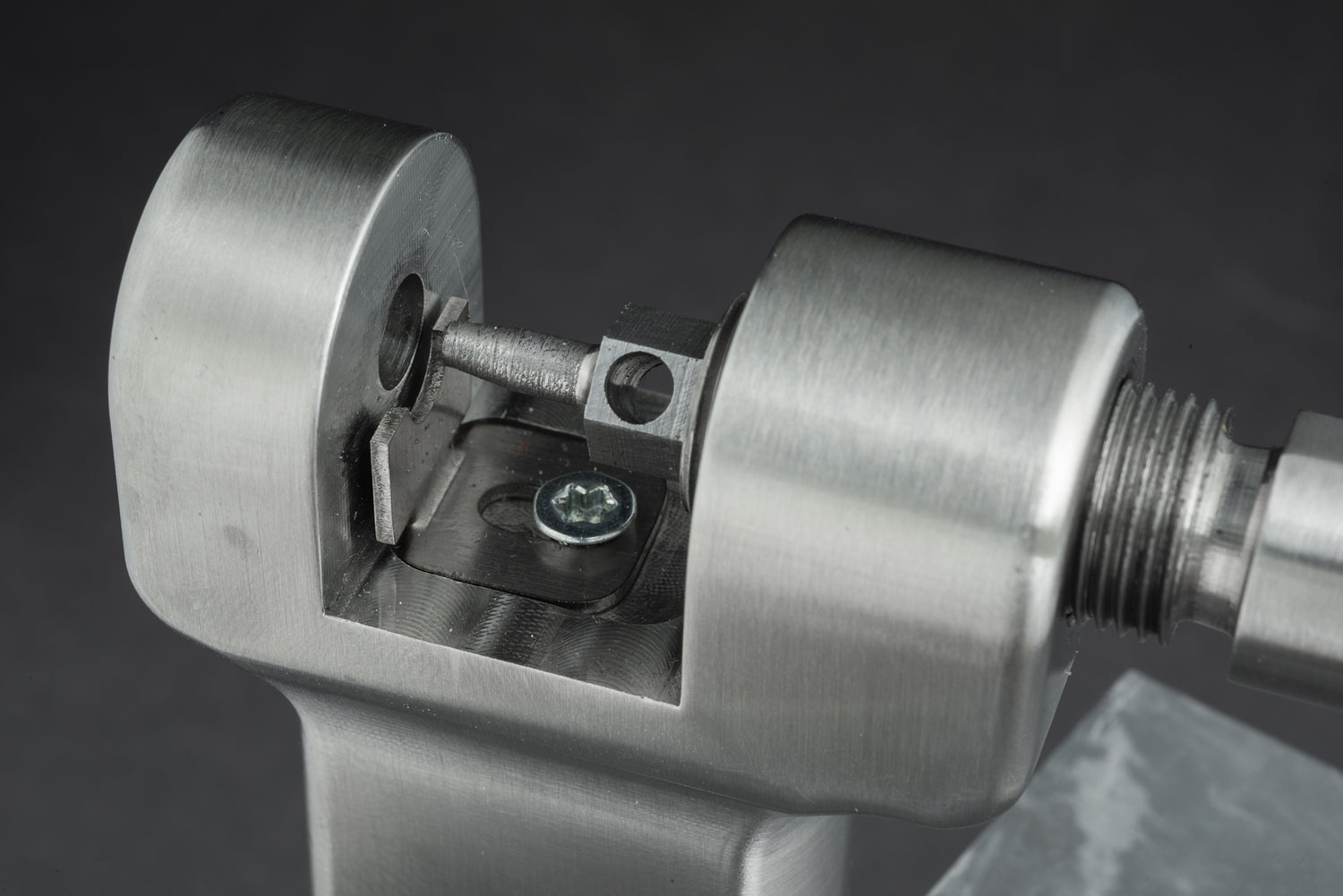 Eine Nahaufnahme des Kettennieters „Optimize Kettennieter“ der Optimize GmbH im Einsatz, bei der der Metallstift einen Kettengliedstift herausdrückt. Das aus Edelstahl gefertigte und mittels CNC-Fräse präzisionsbearbeitete Werkzeug hebt sich mit seiner silbernen Oberfläche deutlich vom sanft unscharfen grauen Hintergrund ab.