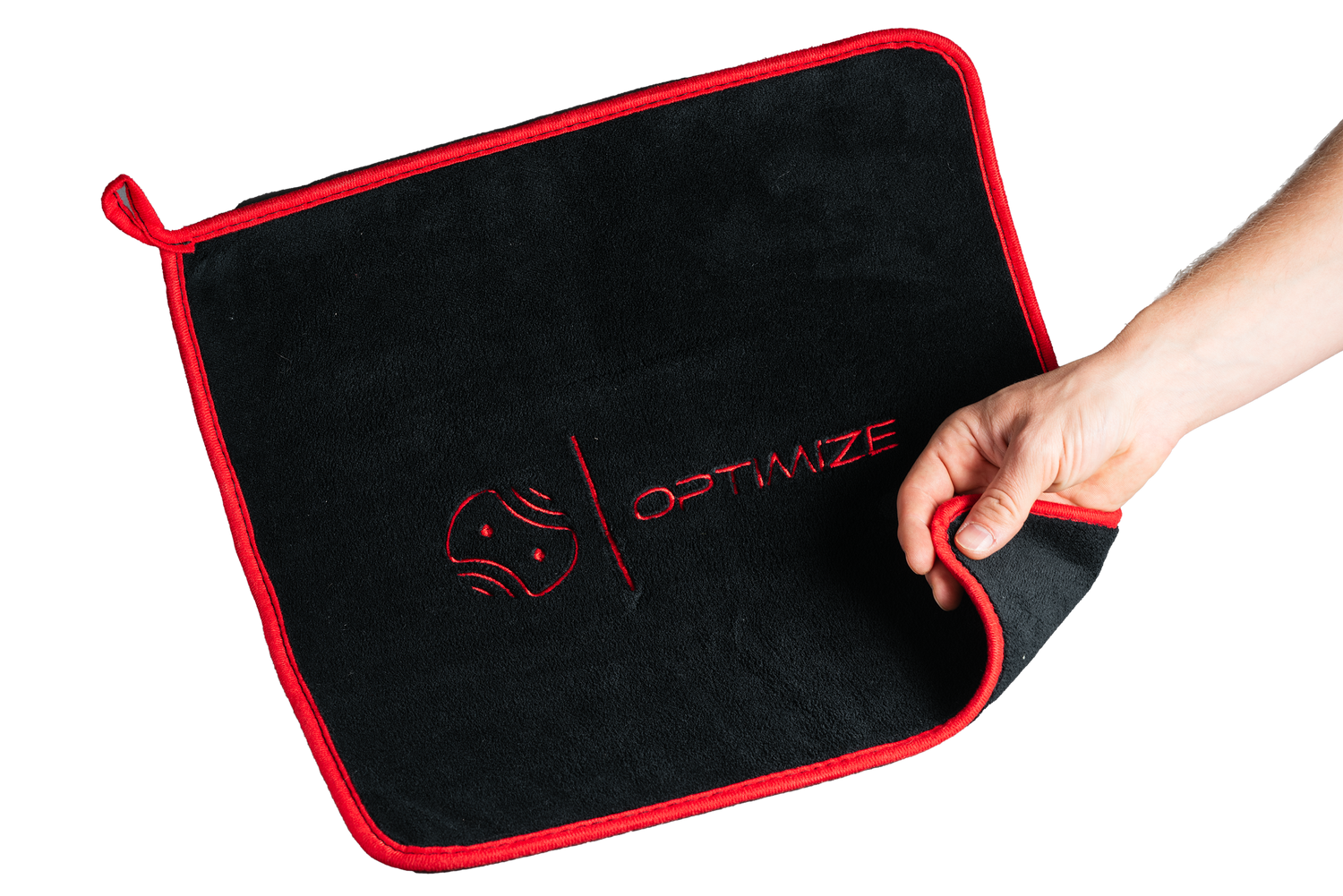 Eine Hand hält das schwarze Optimize Premium Mikrofasertuch der Optimize GmbH mit roter Umrandung, einer Eckschlaufe und dem rot gestickten Schriftzug