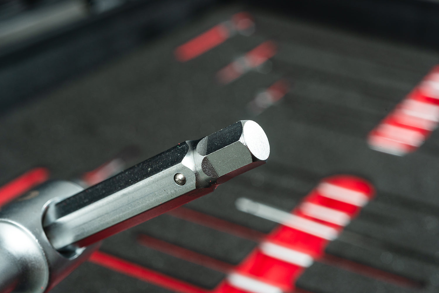 Eine Nahaufnahme eines Sechskant-Metallwerkzeugs in einem Steckschlüssel, mit weiterem Bike-Werkzeug in einem schaumstoffgefütterten Optimize Werkzeugkoffer der Optimize GmbH - ideal für jedes ordentliche Ordnungssystem.