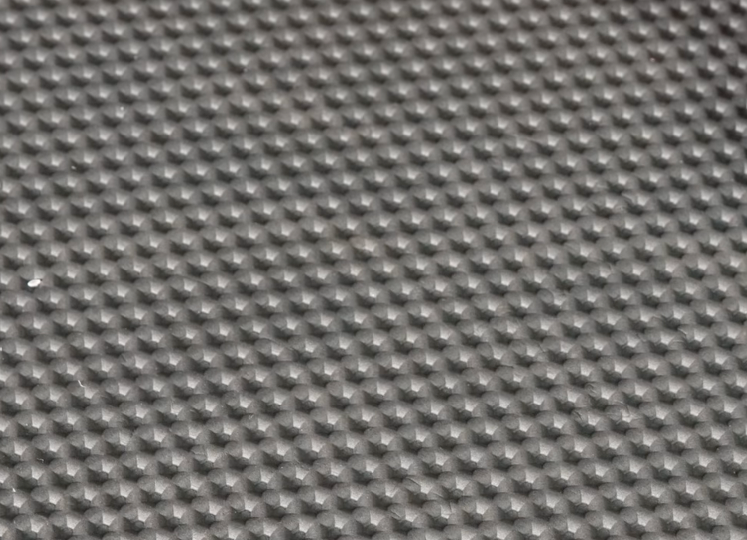 Eine Nahaufnahme der Optimize GmbH Indoor Matte zeigt die strukturierte graue Oberfläche mit sich wiederholenden, pyramidenförmigen Erhebungen, die erstklassige Dämpfung und Komfort für Smart-Trainer-Workouts bieten.