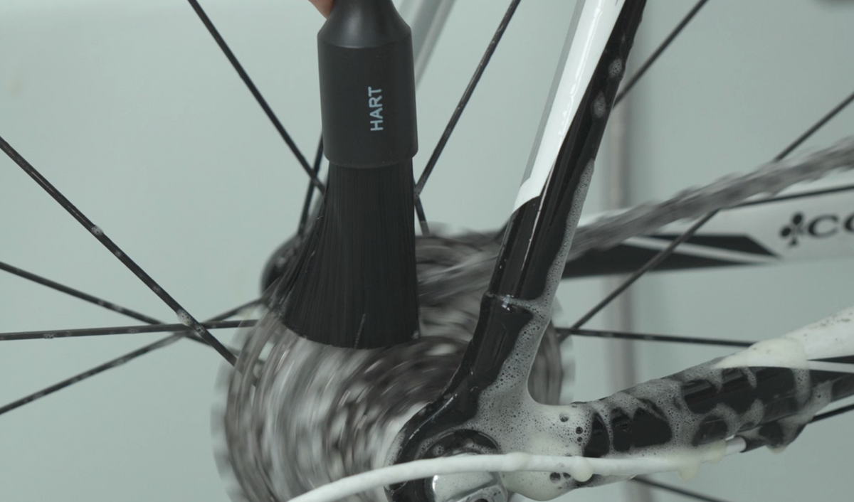 Eine Hand reinigt mit einer Bürste aus dem Pinselset Fahrrad Detailing eine mit Seife bedeckte Fahrradkassette.