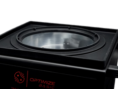 Nahaufnahme eines schwarzen Optimize Automatik Wachskochers 2.0 der Optimize GmbH, mit großer runder Glaslinse oben und roter Aufschrift "OPTIMIZE BASIC" an der Seite. Bietet eine präzise Temperatursteuerung, dargestellt vor einem schlichten weißen Hintergrund.
