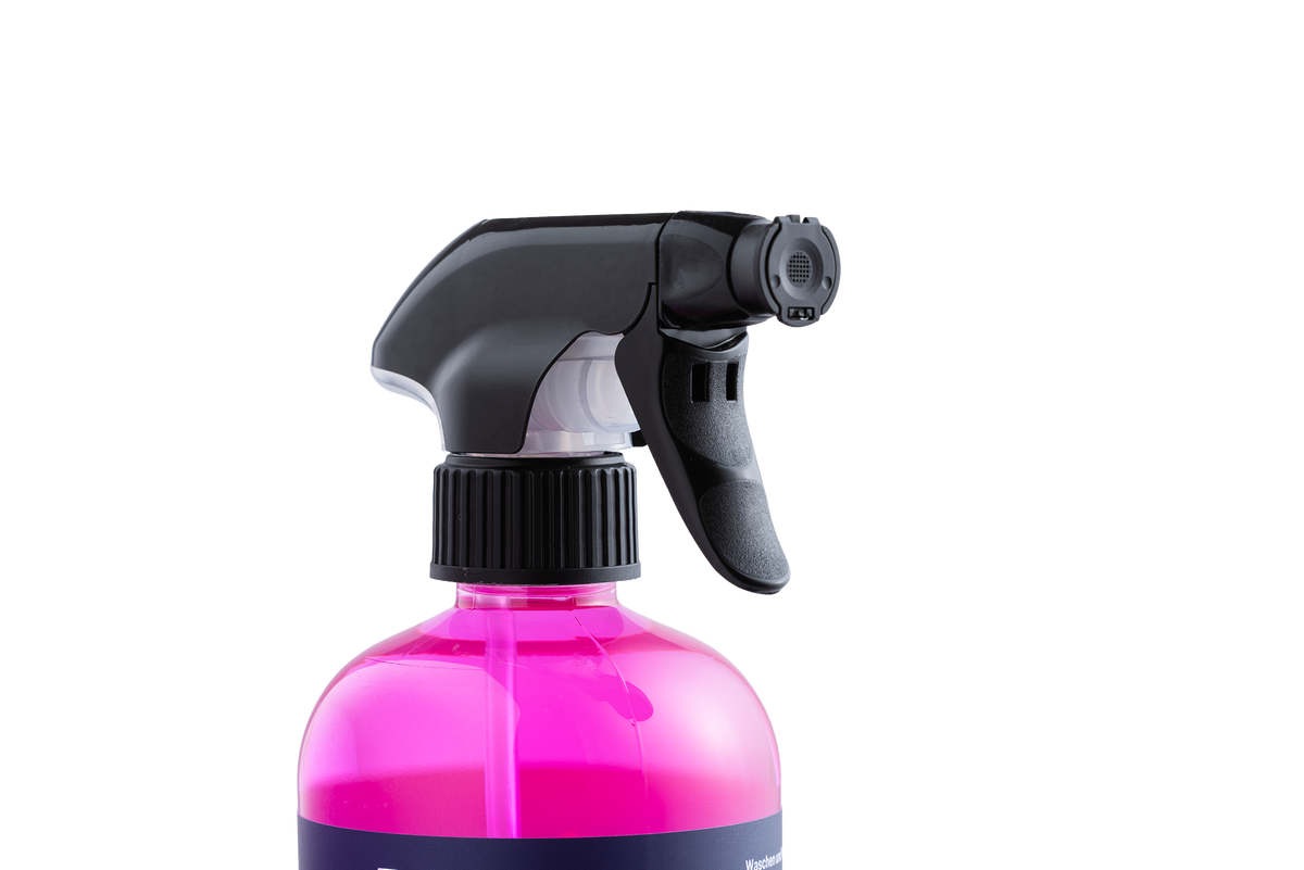Eine durchsichtige Kunststoff-Sprühflasche der Firma KOM Duschen GmbH mit dem Produkt Waschen und Versiegeln – gebrauchsfertig, gefüllt mit leuchtend pinkfarbenem Wachsfilm und versehen mit einem schwarzen Sprühkopf.