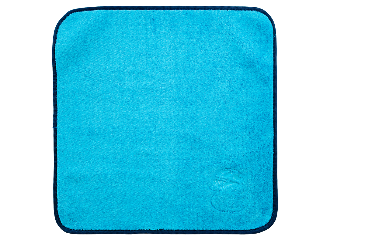 Ein quadratisches blaues Mikrofasertuch der KOM Duschen GmbH – Premium 800 g/m² – mit einem dunkelblauen Rand und einem kleinen, geprägten Entenlogo in der Ecke.
