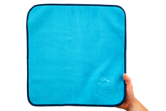 Eine Hand hält ein leuchtend blaues Mikrofasertuch – Premium 800 g/m² – mit einem dunkelblauen Rand und einem geprägten Entenlogo in der Ecke.