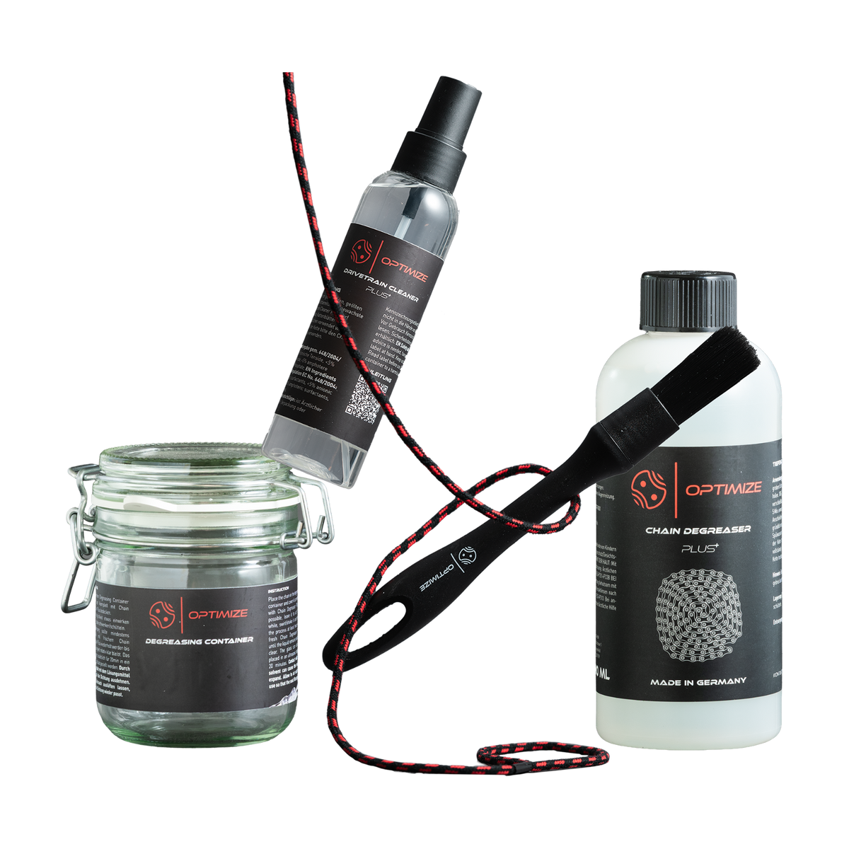 Ein Entfettungs-Set bestehend aus einem Glasbehälter, einer Sprühflasche mit Antriebsstrangreiniger, einer Flasche Kettenentfetter und einer Reinigungsbürste mit schwarz-rotem Griff.